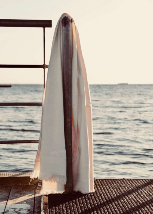 White WAY beach towel hanging on rail by the sea