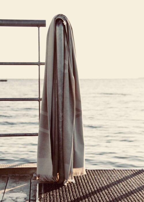 Grey WAY beach towel hanging on rail by the sea