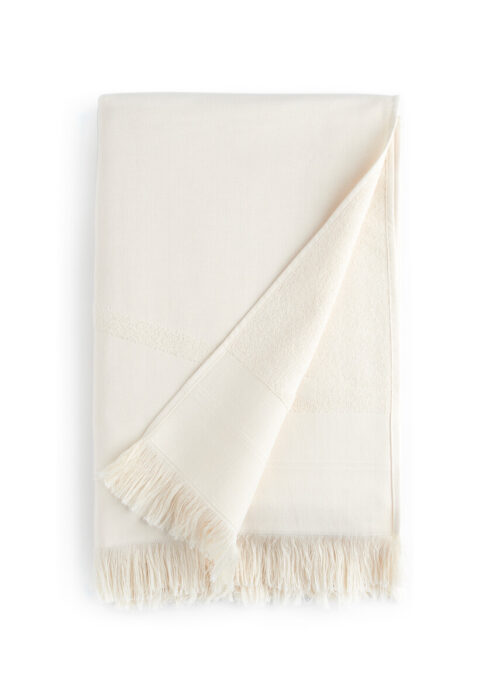 Folded white WAY beach towel with woven front and terry back and fringes