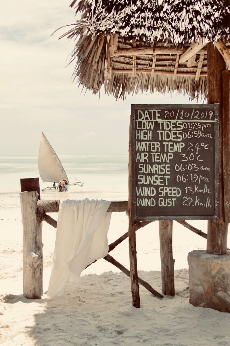 White WAY beach towel on wooden rail with sea and boat in the background