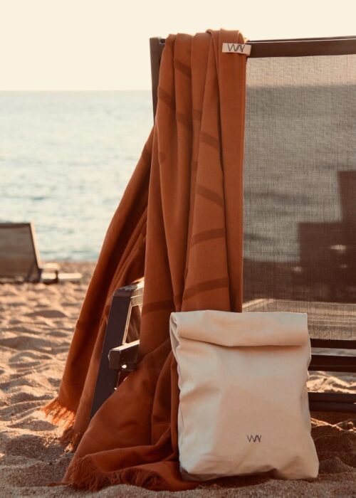 Brown WAY beach towel hanging on chair by the sea