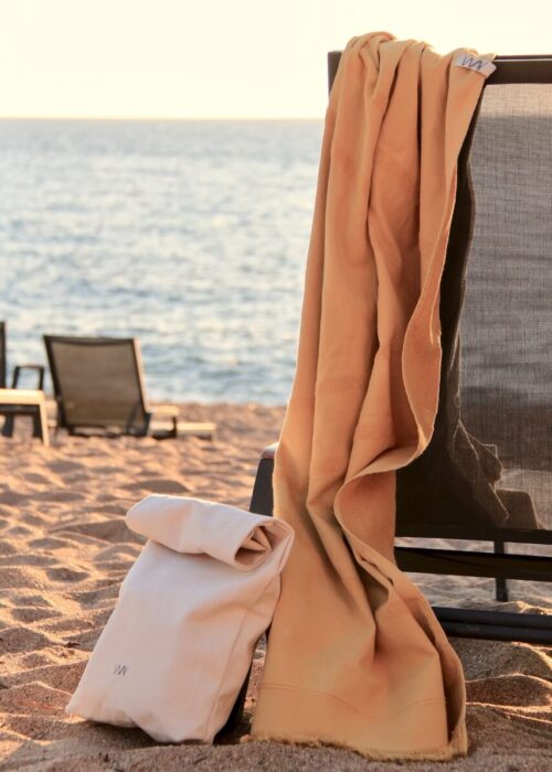 Yelllow WAY beach towel hanging on chair by the sea