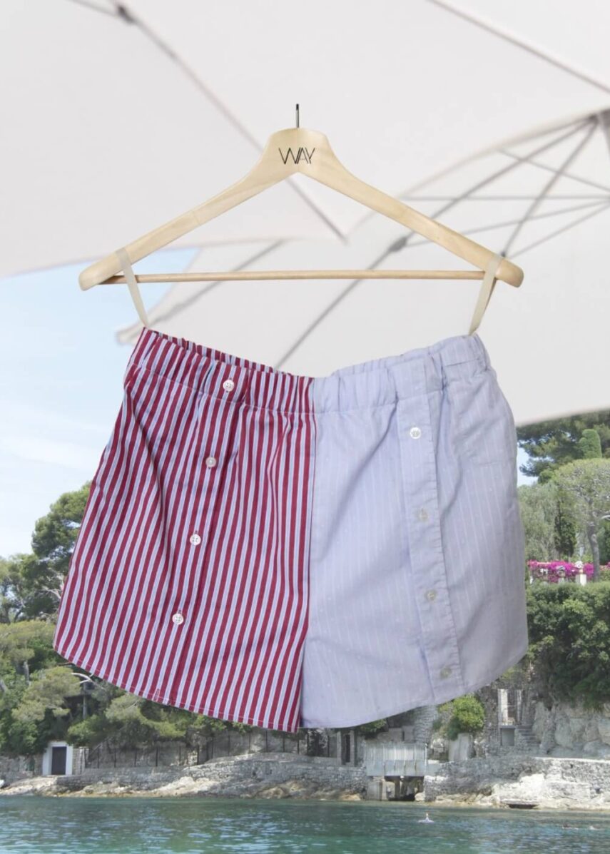 Upcycled blue striped SUN Shorts from WAY collaboration with Salvation Army with beach in back ground