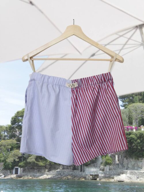 Upcycled blue striped SUN Shorts from WAY collaboration with Salvation Army with beach in back ground