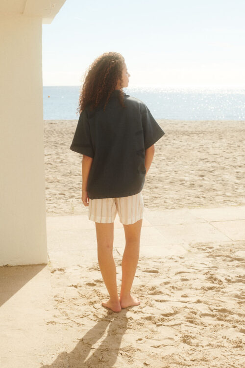 WAY model wearing Bilbao Shirt in dark grey from the back on the beach
