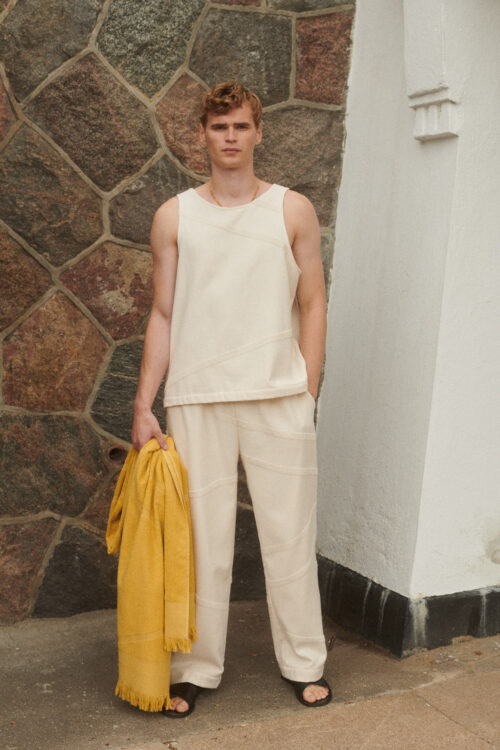 WAY Elba Pants in SHELL cream white on male model holding a yellow beach towel