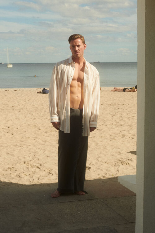 Man wears WAY turquesta shirt open with a towel around his waist.